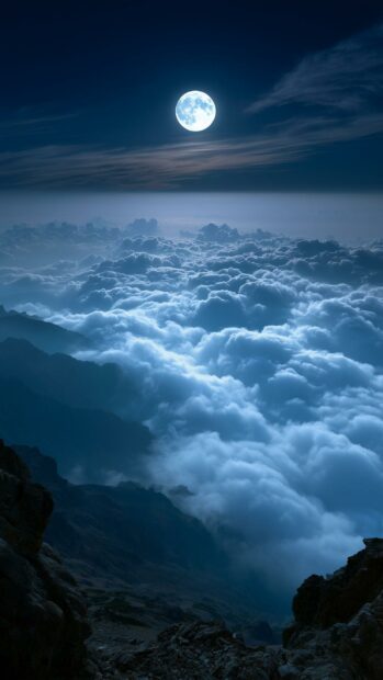 A dramatic moon wallpaper showing a bright full moon shining above a vast sea of blue clouds and dark mountain peaks