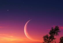 Vibrant Moon Wallpaper with a crescent moon reflecting on a lake during a colorful sunset with purple and orange hues