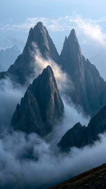 Mountain wallpaper depicting dramatic jagged peaks emerging from thick clouds and fog