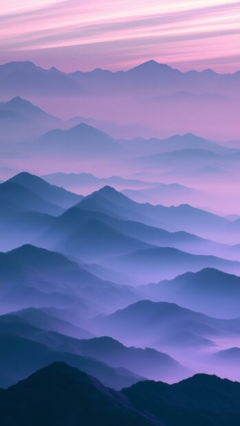 An aesthetic mountain wallpaper featuring misty layers of peaks in soft purple and blue gradient hues
