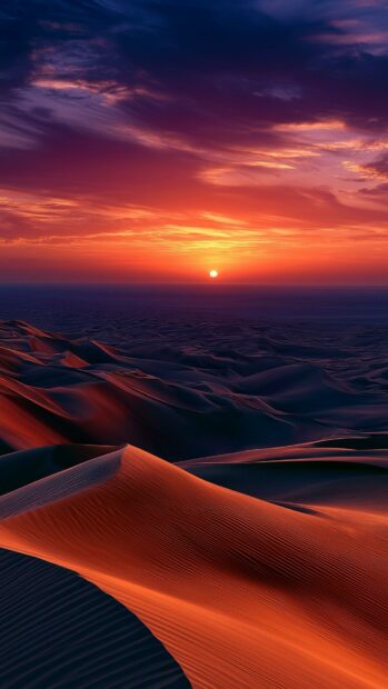 A dramatic nature wallpaper showcasing desert dunes under a vibrant sunset sky with rich orange and purple hues