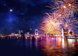 A stunning New Year Aesthetic Wallpaper featuring a city skyline at night with vibrant fireworks exploding over the water and a shooting star in the dark sky