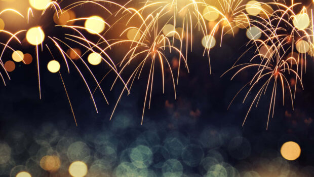 A stunning New Year aesthetic wallpaper showcasing golden fireworks exploding in a dark night sky with shimmering bokeh lights illuminating the bottom