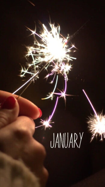 New Year Aesthetic Wallpaper showing a hand holding a bright sparkler with 'JANUARY' text on a dark background
