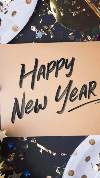 A New Year Aesthetic Wallpaper showing "Happy New Year" written on a golden card surrounded by confetti and party elements