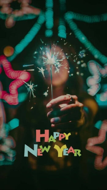New Year Aesthetic Wallpaper with a person holding a sparkling sparkler and colorful 'Happy New Year' text at the bottom