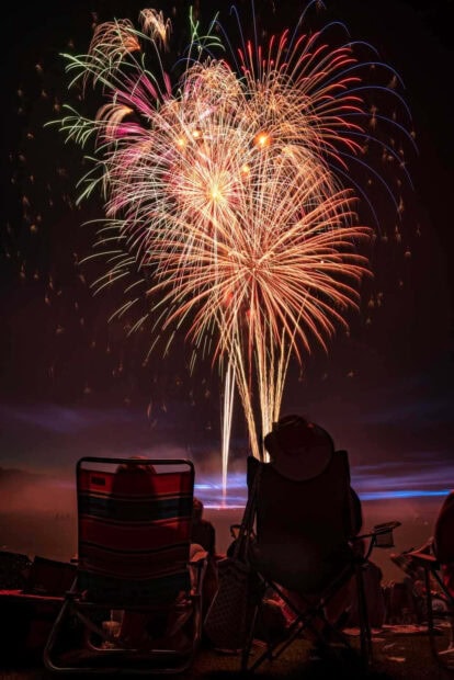 New Year Aesthetic Wallpaper featuring people in chairs watching a vibrant fireworks display at night