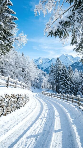 A snow-covered alpine road with mountain peaks in the background under a clear blue sky