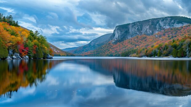 A peaceful lake reflecting the colors of autumn foliage with mountains in the background, Country HD Wallpaper for Desktop.