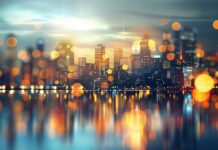 City skyline at night with cool twinkling lights and reflections.