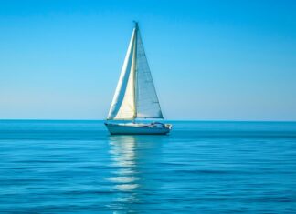 Ocean HD background with a quiet ocean with a lone sailboat in the distance.