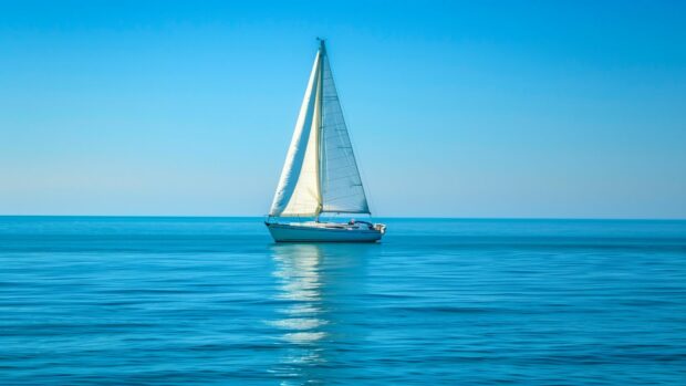 Ocean HD background with a quiet ocean with a lone sailboat in the distance.
