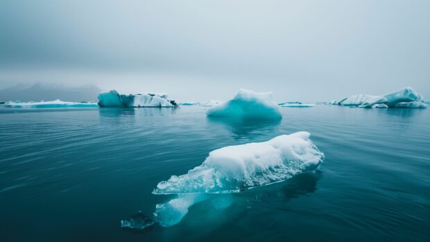 Ocean background with a cold winter ocean with floating icebergs and a gray, overcast sky.