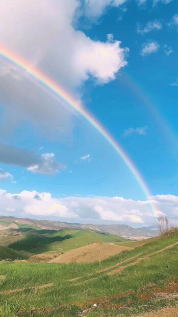 A rainbow stretching across a picturesque countryside scene, beautiful iPhone wallpaper.