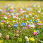 A cheerful Easter HD wallpaper with colorful eggs scattered in a meadow, with vibrant flowers and green grass, bright spring sunshine