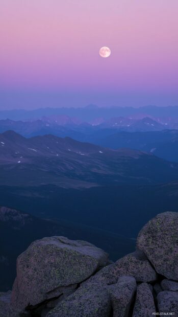 A full moon glowing brightly above a serene mountain range, casting soft light on the rugged peaks and gentle valleys.