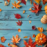 Vibrant autumn pumpkins and colorful fallen leaves arranged on a bright blue wooden surface, capturing the essence of fall décor and seasonal festivities.