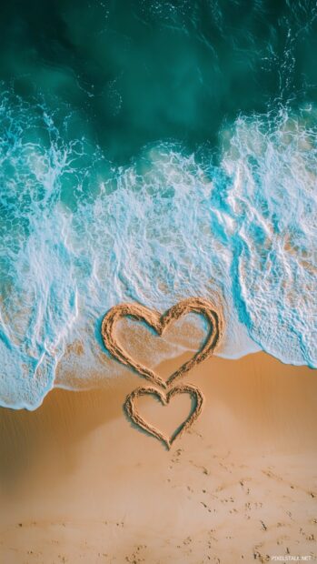 Two intertwined hearts drawn in the sand on a beach, with waves gently approaching, symbolizing everlasting love.