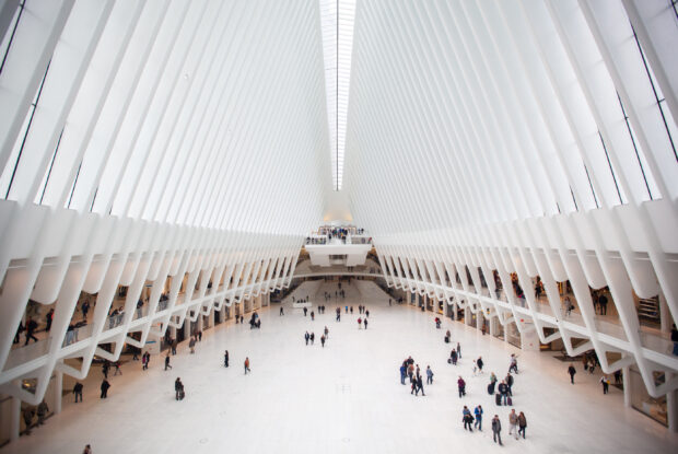 Futuristic modern building interior with white architectural design and visitors walking in open space, high ceilings, and sleek lines.