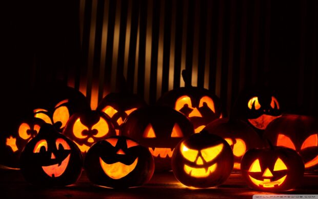 Spooky Halloween pumpkins with glowing carved faces and expressions, eerie illumination, dark background, festive holiday decoration, celebrating Halloween night.