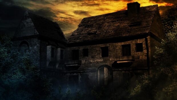 Haunted abandoned house with broken windows and dark night sky with orange clouds.