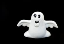 Whimsical ghost figurine with a smiling face and outstretched arms, celebrating Halloween with playful joy, against a black background.