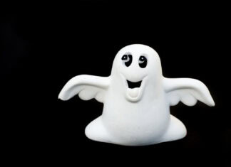 Whimsical ghost figurine with a smiling face and outstretched arms, celebrating Halloween with playful joy, against a black background.