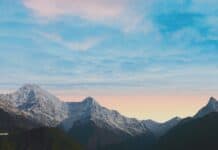 Snow-capped mountain range during sunrise with colorful sky in the background.