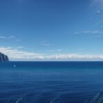 Captivating 4K wallpaper of a sailboat gliding across a shimmering blue ocean on a sunny day