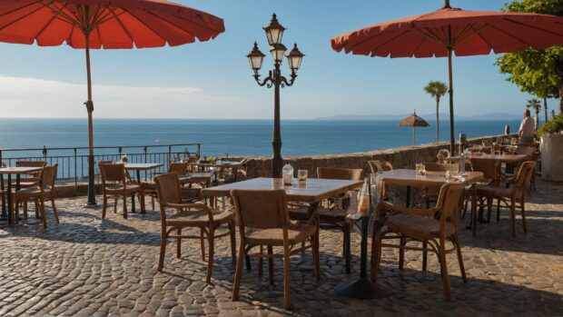 Charming seaside cafe with tables on the cobblestone sidewalk, parasols, and a view of the ocean.