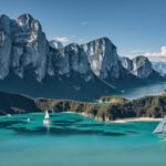 Scenic 4K wallpaper of a sailboat gliding across a shimmering blue lake on a calm summer day