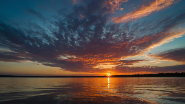Summery sky with a colorful sunset reflecting off calm waters.